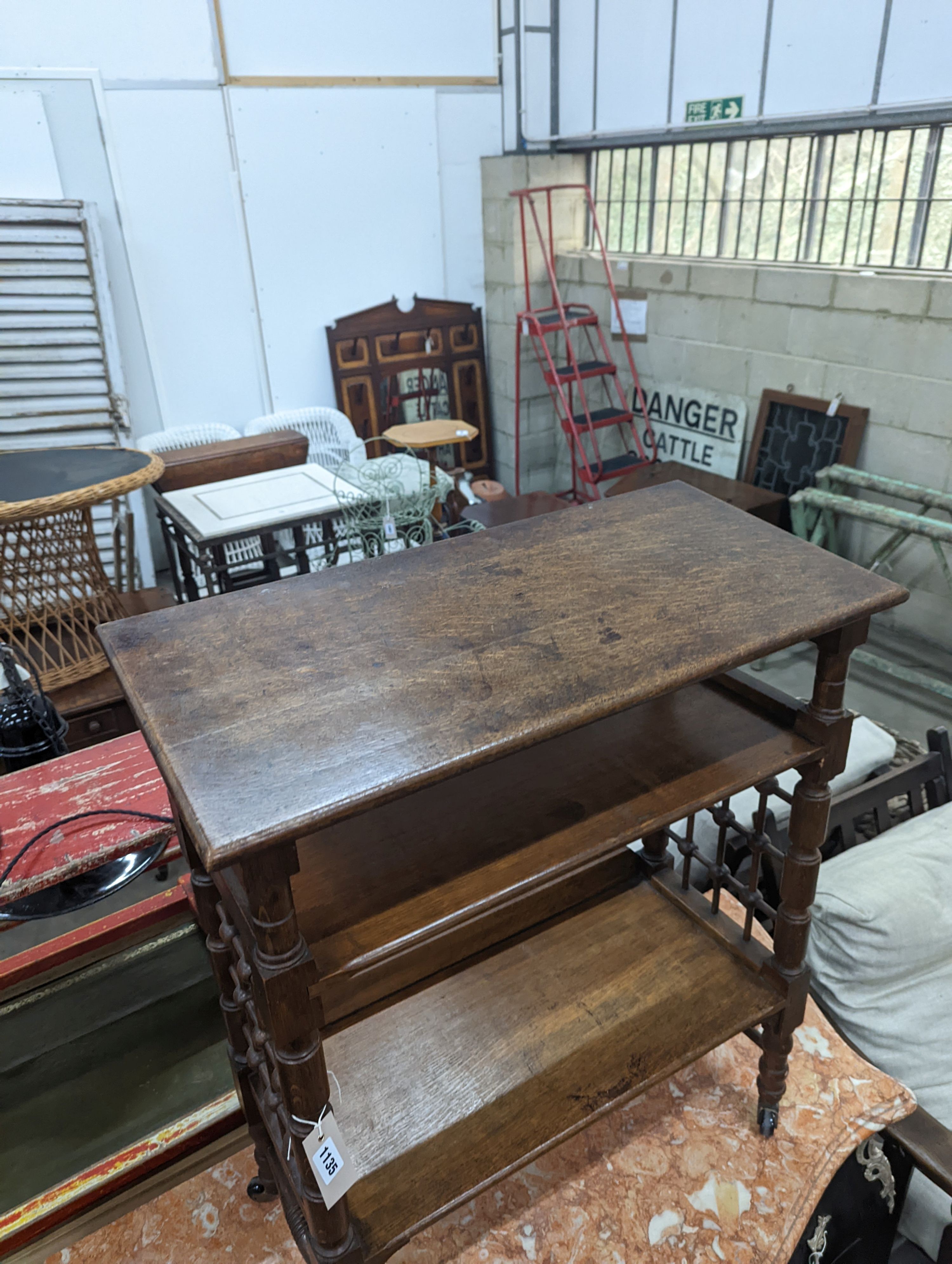 A late 19th century Continental oak three tier Liberty style table with slant top, width 70cm, depth 29cm, height 78cm